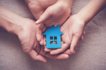 hands holding a blue paper house