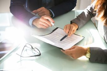 Two business people examining a document over a glass desk