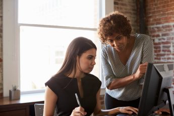 Couple of women looking at a computer screen.