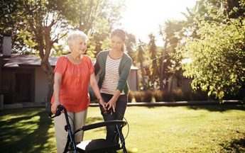 Younger woman assisting an older woman with a walker.