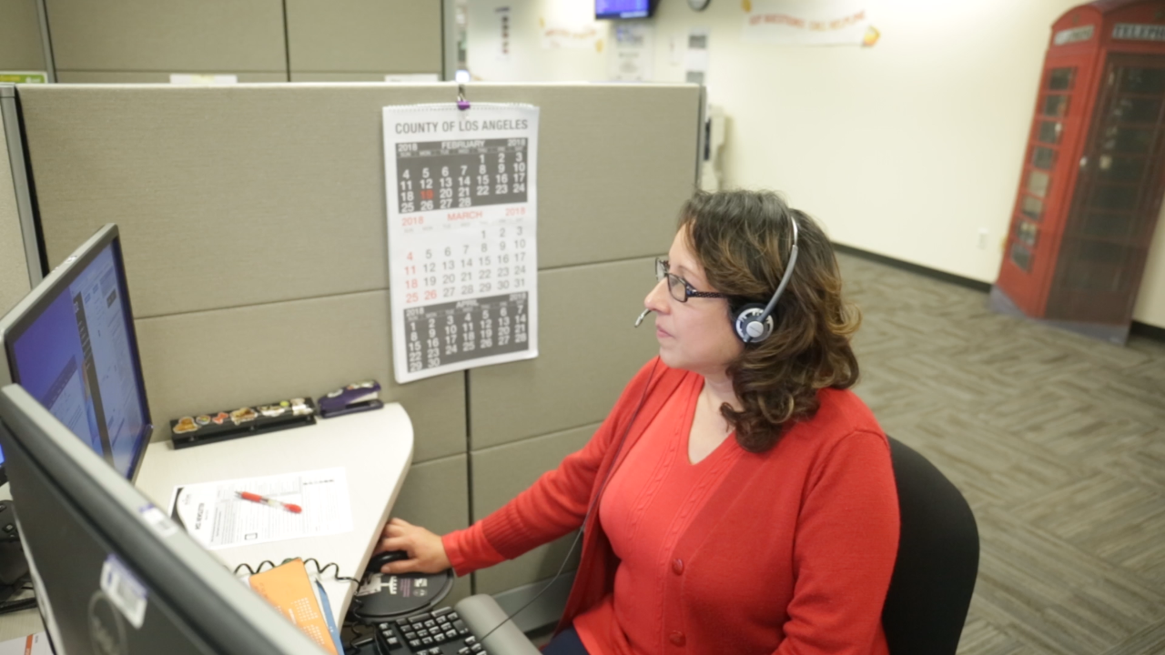 Lady in red sweater assisting customer over the phone 
