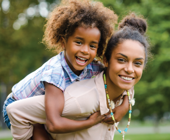 Young female with a female child on her back both smiling