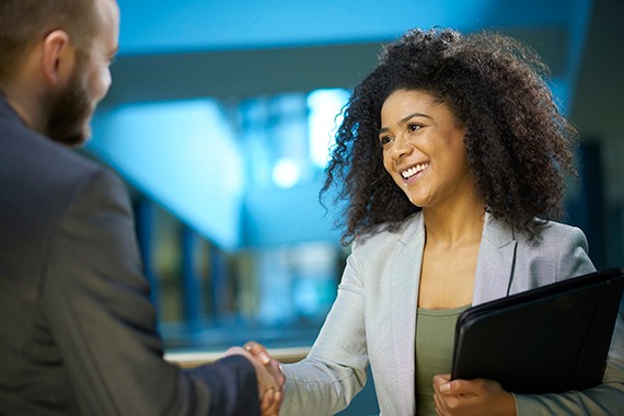 Young confident businesswoman shakes the hand of her potential new employer at her interview