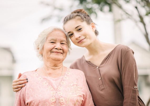 Happy young caucasian woman hugging elderly Asian woman outdoor