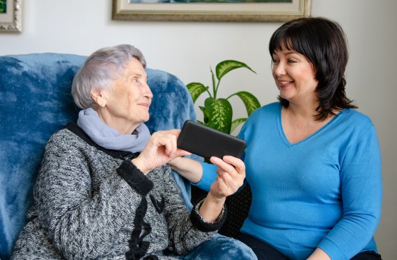 Caring volunteer came home to an elderly lady to teach her how to use a smartphone.
